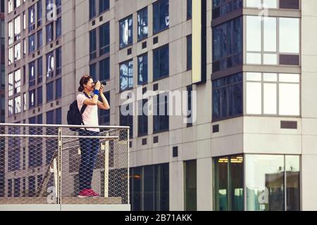 Photographe féminin prend des photos d'architecture à New York, couleur appliquée, Etats-Unis. Banque D'Images