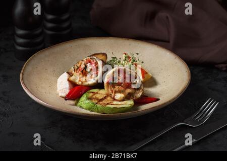 Petits pains de dorado, courgettes et pommes de terre sur une plaque à fond sombre. Banque D'Images