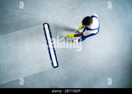 Homme Avec Balai À Franges Et Panneau De Sol Humide Banque D'Images
