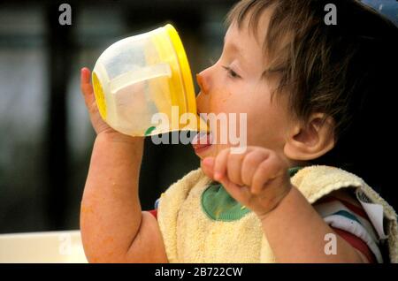 Austin Texas USA bébé garçon de dix mois qui boit dans une tasse à bec. M. ©Bob Daemmrich Banque D'Images