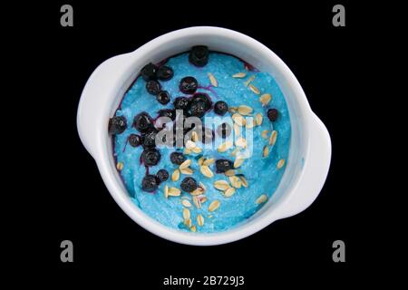 Fromage cottage avec confiture, bleuets frais et graines de citrouille dans un bol en céramique isolé sur fond noir. Petit déjeuner savoureux et sain Banque D'Images