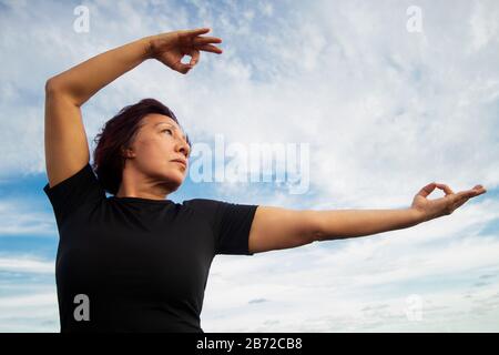 Femme active senior pratiquant le Tai chi sur la plage. Banque D'Images