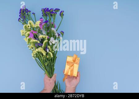 Mains tenant un bouquet de fleurs sauvages et une boîte cadeau Banque D'Images