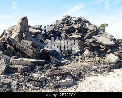 Montagne d'asphalte, chaussée en béton et débris de stationnement sur le site de démolition de route, couverture de grille métallique pour drain d'égout, drain d'égout en béton Banque D'Images