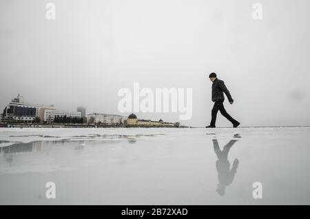 L'homme traverse la rivière. Route inondée sur glace Banque D'Images