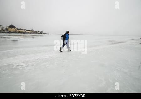 L'homme traverse la rivière. Route inondée sur glace Banque D'Images