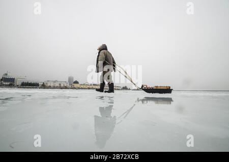 L'homme traverse la rivière. Route inondée sur glace Banque D'Images