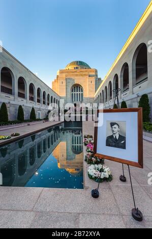Vue sur la piscine de la cour, les couronnes cérémonielles et les portraits de soldats encadrés menant à la citadelle et au tombeau du soldat inconnu à Canberra. Banque D'Images