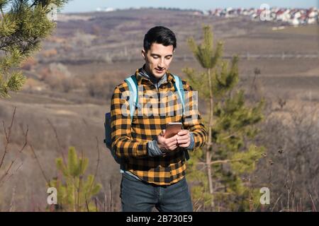 printemps à l'extérieur. beau homme à la campagne en utilisant le téléphone pour naviguer Banque D'Images