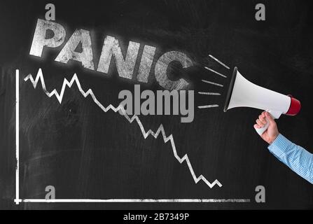 Crash et panique au concept de bourse et de marchés financiers, tenant main mégaphone avec mot PANIQUE contre graphique négatif sur tableau noir Banque D'Images