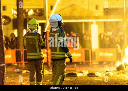 Pompiers autour d'un feu causé par une falla Valenciana contrôlant les flammes de l'incendie. Banque D'Images