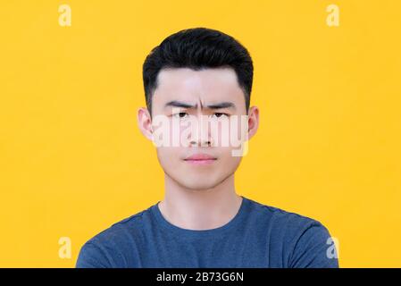 Gros portrait de jeune homme asiatique mécontent en colère face isolé sur fond jaune Banque D'Images