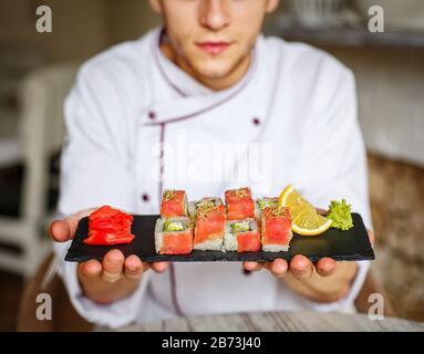 Le chef sushi tient le set de sushis sur un plateau en pierre. Délicieux plats japonais. Sushi au saumon Banque D'Images