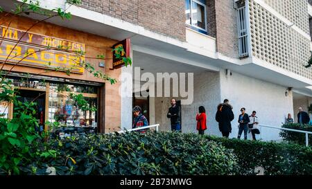 Madrid, Espagne - 13 mars 2020: Les gens pratiquent la distanciation sociale en dehors d'un magasin de tabac à Sanchinarro, Madrid, Espagne Banque D'Images