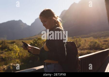 Vue latérale de la femme avec un sac à dos regardant son téléphone Banque D'Images