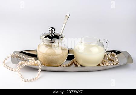 Bol à sucre et milkman sur un plat de service argent avec perles de perle isolées sur fond blanc. Banque D'Images