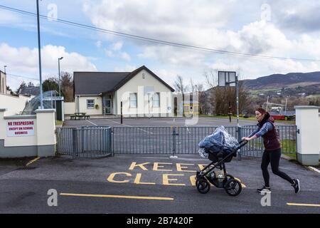 Ardara, Comté de Donegal, Irlande. 13 mars 2020. Une jeune mère passe devant l'aire de jeux généralement animée à l'heure du déjeuner. L'école est maintenant fermée en raison du coronavirus Covid-19, précautions dans toute la République qui ont été annoncées hier. Banque D'Images