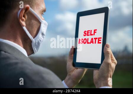 Homme d'affaires portant un masque chirurgical utilisant son ordinateur tablette à l'extérieur comme bureau mobile en auto-isolation Banque D'Images