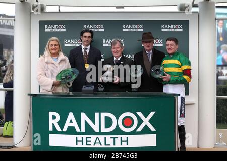 Le propriétaire J. P. McManus (centre) avec le formateur Willie Mullins (2ème à droite) et le jockey Barry Geraghty (à droite) après Saint Roi a remporté le Randox Health County handicap Hurdle au cours du quatrième jour du Cheltenham Festival à l'hippodrome de Cheltenham. Banque D'Images