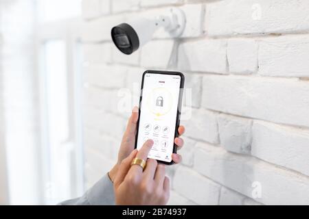 Contrôle de la surveillance vidéo et de l'alarme à domicile avec une application mobile, gros plan sur un smartphone avec une application lancée. Concept de systèmes de sécurité domestique sans fil Banque D'Images