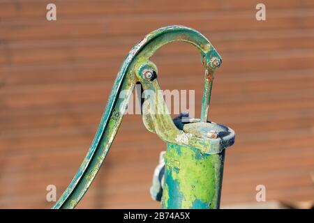 Vue rapprochée de la poignée d'une pompe à eau verte. Un peu rouillé et recouvert de glace (par temps froid). Pour pomper manuellement de l'eau. Banque D'Images