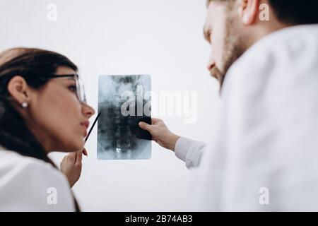 Médecins en couches blanches examinant l'image de radiographie spinale Banque D'Images