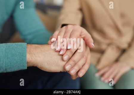 Gros plan d'une femme qui soutient l'homme et tient sa main pendant qu'ils sont assis sur le canapé Banque D'Images