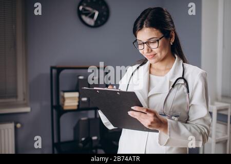 Médecin de sexe féminin prenant des notes médicales dans les documents Banque D'Images