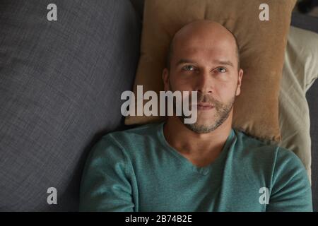 Vue à grand angle de l'homme mûr allongé sur le canapé sur l'oreiller et rêvant de quelque chose Banque D'Images