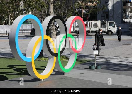 Tokyo, Japon. 12 mars 2020. Les piétons portant des masques marchent devant les anneaux olympiques à Tokyo, Japon, 12 mars 2020. Le ministère japonais de la santé et les gouvernements locaux ont déclaré vendredi que le nombre d'infections à COVID-19 avait augmenté de 21 à 697 cas au Japon à 18 h 30, heure locale ici. Le nombre de morts est actuellement de 26, selon le ministère de la santé, avec le chiffre incluant ceux du navire de croisière Diamond Princess, qui a été mis en quarantaine à Yokohama, près de Tokyo. Crédit: Du Xiaoyi/Xinhua/Alay Live News Banque D'Images