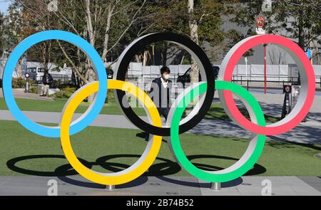 Tokyo, Japon. 12 mars 2020. Un masque piéton passe devant les anneaux olympiques à Tokyo, Japon, 12 mars 2020. Le ministère japonais de la santé et les gouvernements locaux ont déclaré vendredi que le nombre d'infections à COVID-19 avait augmenté de 21 à 697 cas au Japon à 18 h 30, heure locale ici. Le nombre de morts est actuellement de 26, selon le ministère de la santé, avec le chiffre incluant ceux du navire de croisière Diamond Princess, qui a été mis en quarantaine à Yokohama, près de Tokyo. Crédit: Du Xiaoyi/Xinhua/Alay Live News Banque D'Images