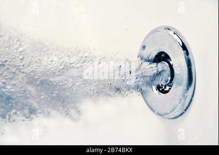 Une buse souffle l'air horizontalement sous l'eau dans une baignoire. Banque D'Images