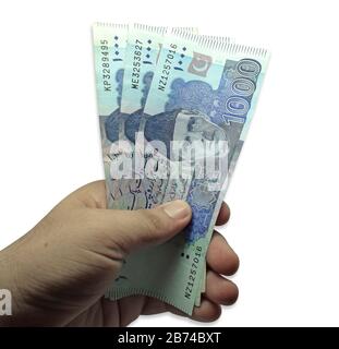 Homme brun tenant plusieurs billets de devises pakistanaises sur fond blanc Banque D'Images