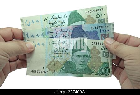 Homme brun tenant plusieurs billets de devises pakistanaises sur fond blanc Banque D'Images