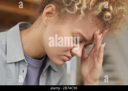 Une jeune femme aux cheveux bouclés a un mal de tête elle est très fatiguée ou elle est en dépression Banque D'Images