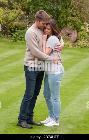 Belle jeune femme enceinte et son partenaire avec leurs bras l'un autour de l'autre Banque D'Images Belle jeune femme enceinte et son partenaire avec leurs bras l'un autour de l'autre Banque D'Images