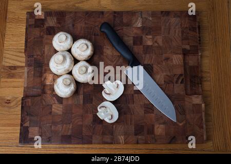 Champignons blancs communs sur une planche à découper avec un couteau Banque D'Images