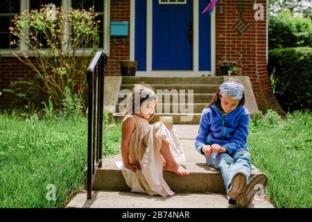 Deux petites filles s'assoient au soleil en parlant l'une à l'autre Banque D'Images