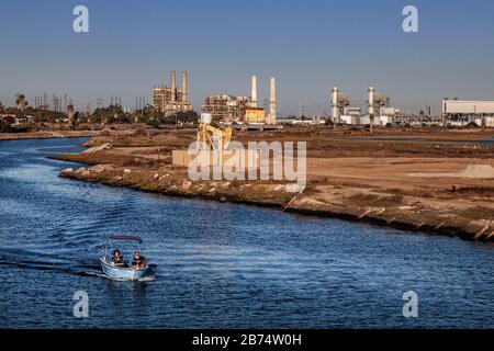Bateau à moteur à Los Cerritos Wetlands avec raffineries de pétrole au loin, long Beach, californie, États-Unis Banque D'Images