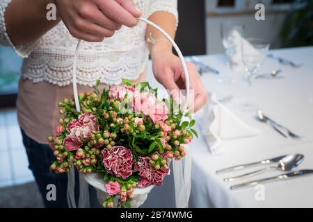 Femme en robe blanche tenant un panier de fleurs pas de visage près. Photo d'un beau panier de mariage tenant par une belle femme. Banque D'Images