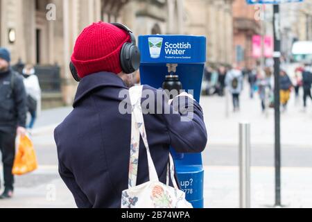 Personne utilisant le point de remplissage d'eau public - Scottish Water Top Tap - Buchanan Street, centre-ville de Glasgow, Ecosse, Royaume-Uni Banque D'Images