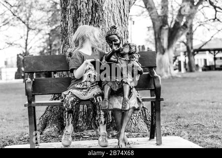 Une petite fille assise sur un banc dans un parc. Photo de haute qualité Banque D'Images