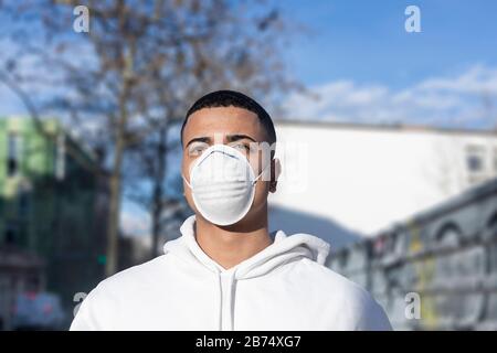 Homme malade portant un masque facial de protection contre les maladies infectieuses transmissibles et comme protection contre le coronavirus dans la place publique. Banque D'Images