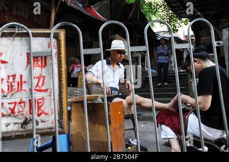 04.08.2012, Chongqing, Chine, Asie - un touriste est en train de faire une pédicure en plein air dans les rues de la vieille ville de Shibati. [traduction automatique] Banque D'Images