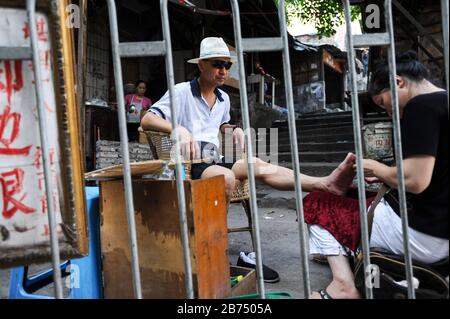 04.08.2012, Chongqing, Chine, Asie - un touriste est en train de faire une pédicure en plein air dans les rues de la vieille ville de Shibati. [traduction automatique] Banque D'Images