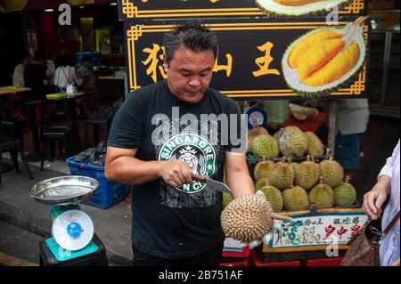 24.02.2019, Singapour, République de Singapour, Asie - un vendeur ouvre une dure fraîche avec un couteau sur un marché de rue à Chinatown. [traduction automatique] Banque D'Images