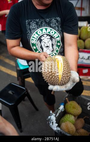 24.02.2019, Singapour, République de Singapour, Asie - un vendeur ouvre une dure fraîche avec un couteau sur un marché de rue à Chinatown. [traduction automatique] Banque D'Images