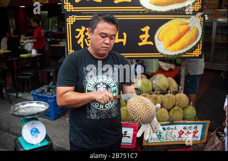 24.02.2019, Singapour, République de Singapour, Asie - un vendeur ouvre une dure fraîche avec un couteau sur un marché de rue à Chinatown. [traduction automatique] Banque D'Images