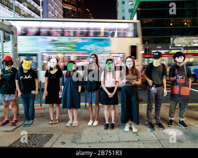 Les manifestants portent toutes sortes de masques et forment une chaîne humaine dans différentes régions de Hong Kong pour protester contre la loi anti-masque. Banque D'Images