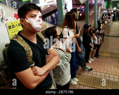 Les manifestants portent toutes sortes de masques et forment une chaîne humaine dans différentes régions de Hong Kong pour protester contre la loi anti-masque. Banque D'Images